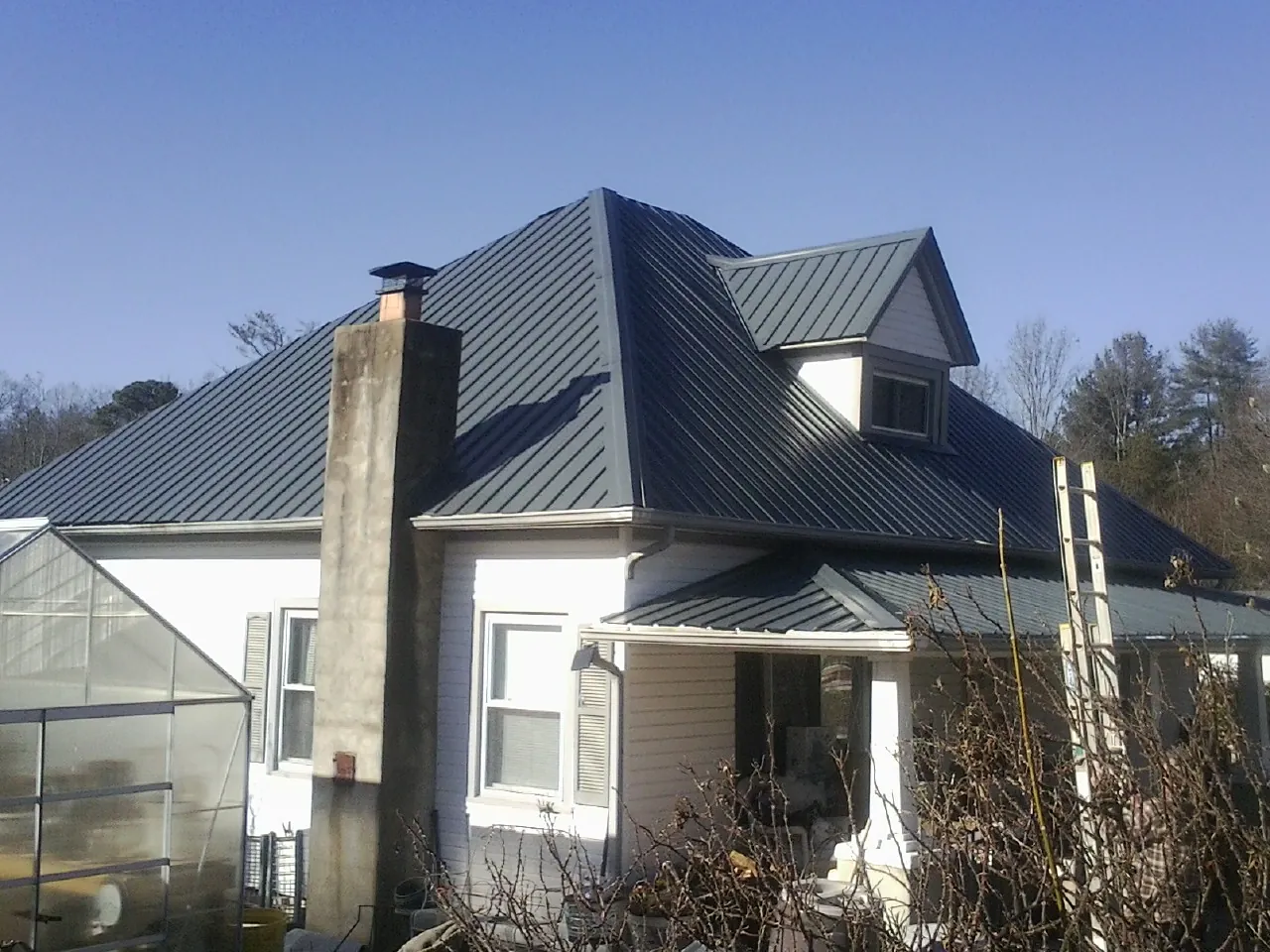 Dark blue standing seam metal roof on a white farmhouse with dormer — Slate & Tile Roof Repair by Roofing Brothers in Intercourse