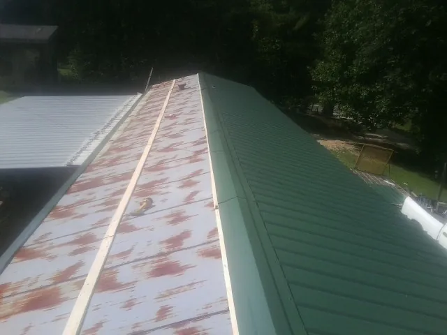 Old rusted panels beside newly installed green metal roofing — Wind Damage Roof Repair by Roofing Brothers in Intercourse