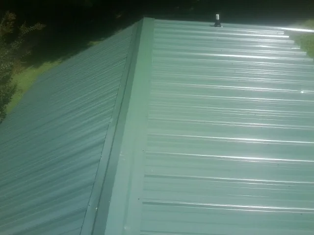 New green metal panels meeting at the ridge of a roof — Flat Roof Repair work by our crew in Intercourse