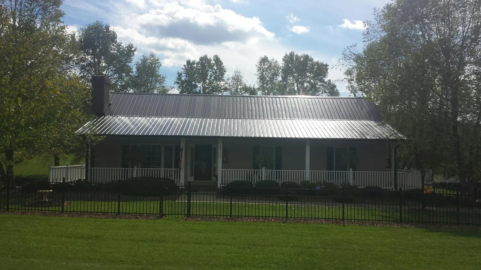 Gray metal roof on a brick ranch with a full width front porch — Gutter Guard Installation work by our crew in Intercourse