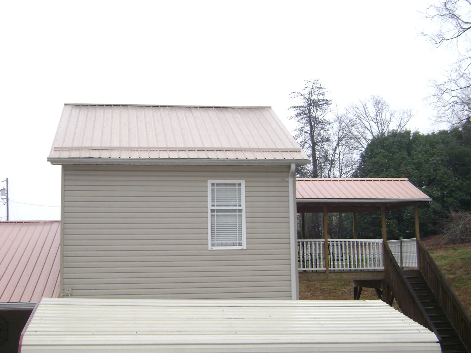 Tan metal roofs on a two story addition and attached porch, from a Roof Replacement job in Intercourse